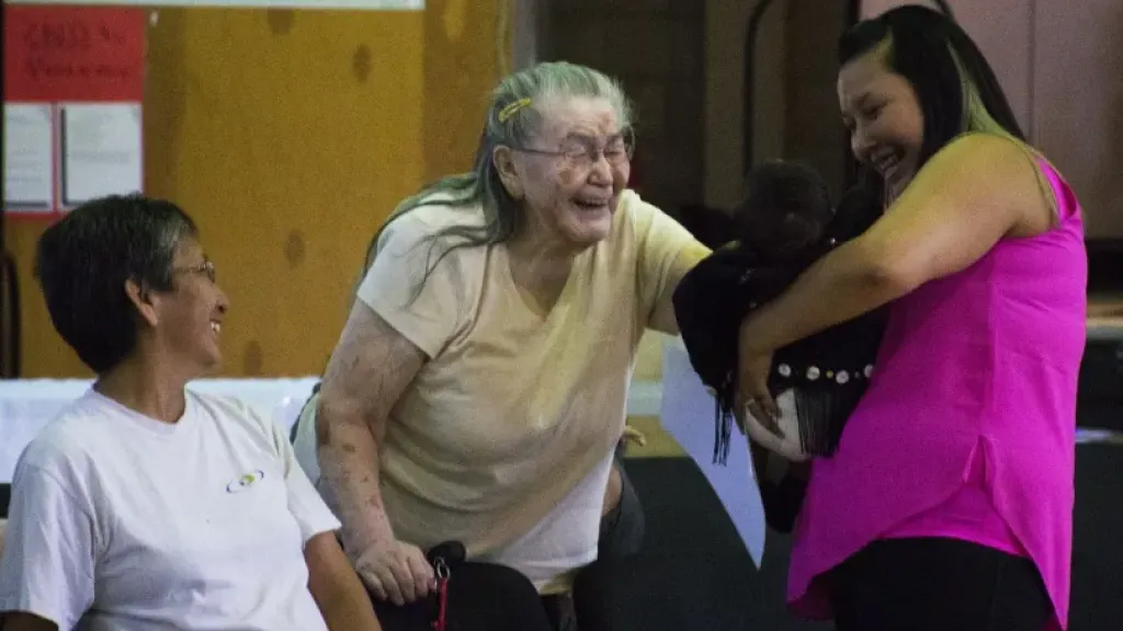 Elderly person smiling while looking at baby
