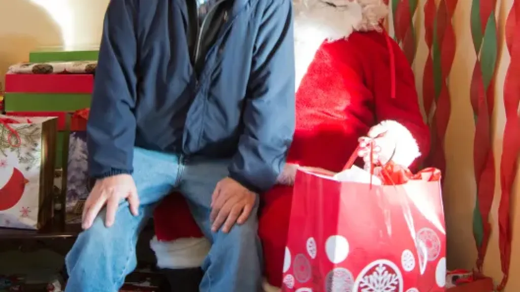 Person smiling while sitting on Santa Claus's knee