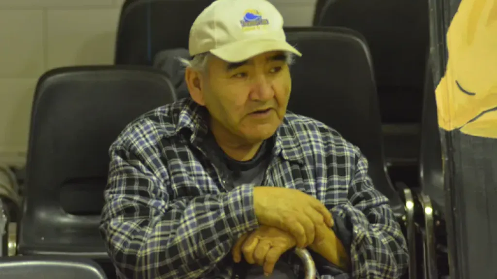 Person with cap and holding walking cane sitting down