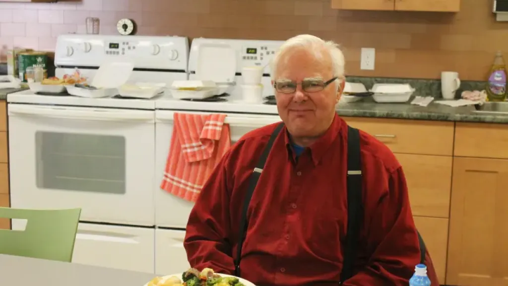 Elderly person sitting with plate of food