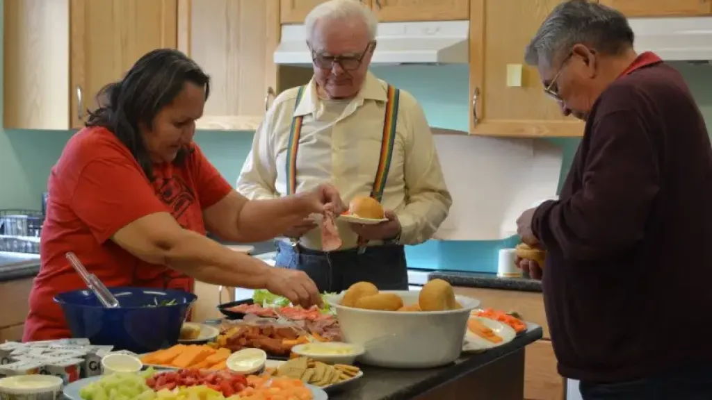 Group of people picking up food around table